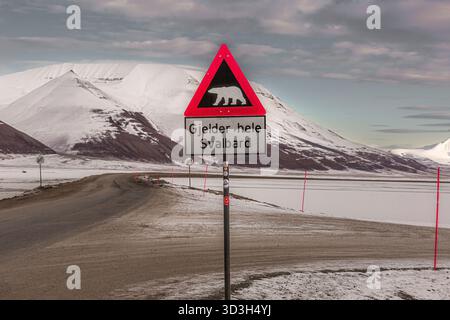 Longyerbeyen, Svalbard, panneau avec un ours polaire sur elle est affiché sur une route dans un paysage enneigé. Le signe est dans une langue étrangère, et c'est un avertissement Banque D'Images