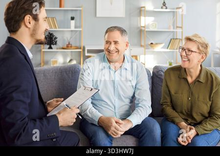 Rencontre amicale du conseiller financier avec le couple senior, discutant des placements et des options d'assurance. Banque D'Images