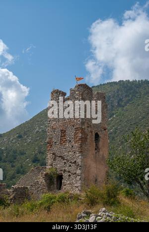 Ruines historiques de château en pierre avec un drapeau national flottant au sommet de l'ancienne tour, sur un ciel bleu avec des montagnes Banque D'Images