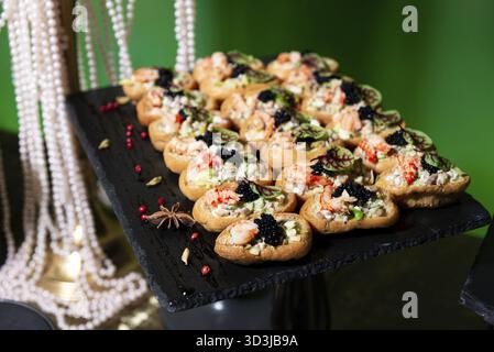 Nourriture, canapés de fruits de mer élégants remplis de crevettes, mélange de salade et recouvert de caviar noir, parfait pour les fêtes et réceptions haut de gamme Banque D'Images