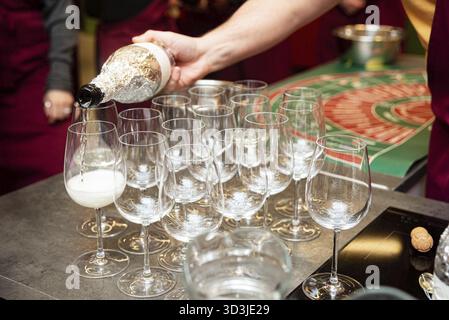 Nourriture, Une personne verse du vin mousseux dans une rangée de verres à vin élégants, préparant des boissons pour une fête ou un événement festif Banque D'Images