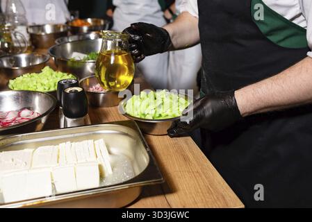 Nourriture, divers légumes fraîchement hachés et fromage feta préparés dans des bols, avec une cruche d'huile d'olive prête à vinaigrer une salade Banque D'Images