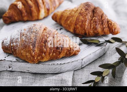 Nourriture, gros plan trois croissants fraîchement cuits avec du sucre en poudre sur un bureau en bois Banque D'Images
