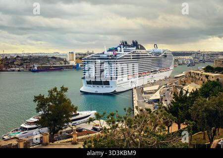 Valletta, Malte - 11.05.2025 : vue aérienne du pittoresque port maltais avec le navire de croisière MSC World Europa amarré sous un ciel nuageux nocturne Banque D'Images