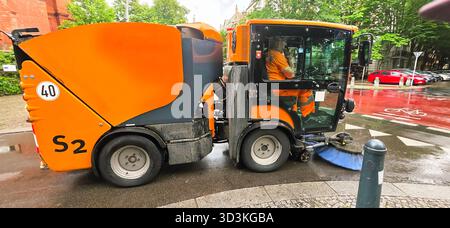 Berlin, Allemagne - 05 juin 2025 : la machine de nettoyage des rues nettoie activement les routes urbaines avec une chaussée humide. Banque D'Images