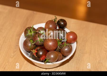 Tomates cerises foncées dans le bol Banque D'Images
