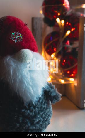 Gnome scandinave avec lumières de Noël, vertical. Père Noël suédois et guirlande de bulbes chauds, gros plan. Décoration de Noël et jouets. Humeur du nouvel an. Banque D'Images