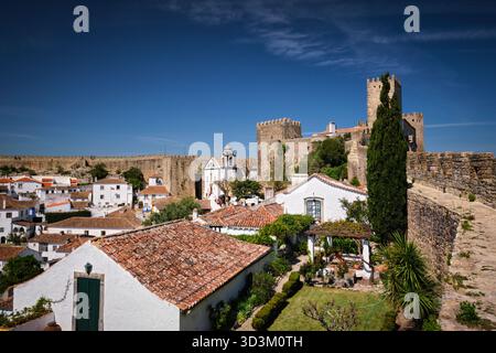 Superbe château d'Obidos surplombant les maisons traditionnelles portugaises et les toits sous un ciel bleu clair. Portugal Banque D'Images