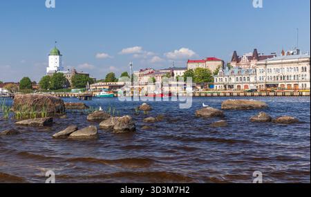 Vyborg, Russie - 27 mai 2024 : une scène de ville côtière dynamique avec un port calme, des bateaux colorés, une tour de château blanche avec un dôme vert, un vieux archi Banque D'Images