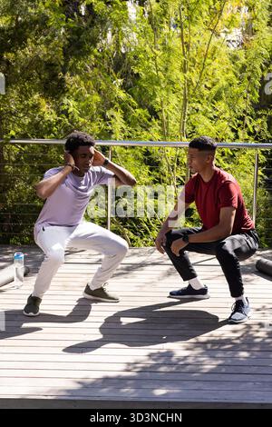 Divers amis masculins squatting et coaching sur le pont dans la cour arrière, avec bouteille d'eau et rouleau de mousse Banque D'Images