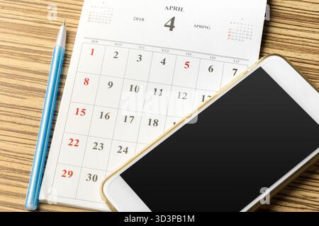 Calendrier et smartphone sur une table en bois montrant le 4 avril avec les détails de la saison de printemps Banque D'Images