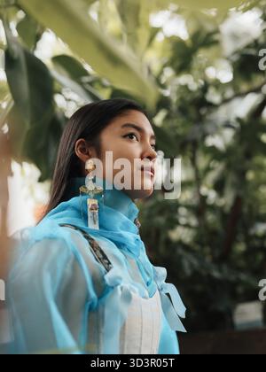 Jeune femme en tenue bleue debout dans un jardin vert luxuriant Banque D'Images