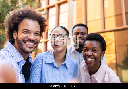 Un groupe diversifié de professionnels souriants se tiennent ensemble à l'extérieur dans un environnement urbain. Ils respirent le travail d'équipe, la collaboration et la positivité, e. Banque D'Images