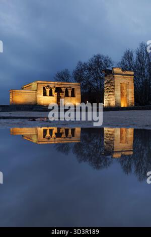 Le temple de Debod, une ancienne structure égyptienne, est illuminé au crépuscule à Madrid, se reflétant dans un étang voisin. Ce monument historique enrichit Banque D'Images