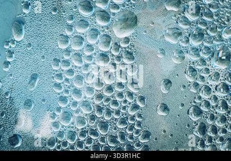 Un plan macro fascinant de gouttelettes d'eau créant des motifs complexes sur une surface texturée. L'image capture la beauté et l'élégance de la nature Banque D'Images