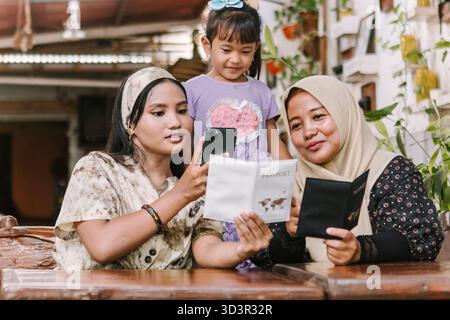 Trois générations d'une famille musulmane d'Asie du Sud-est, y compris grand-mère, mère et fille, partageant un moment ensemble tout en explorant Travel Do Banque D'Images