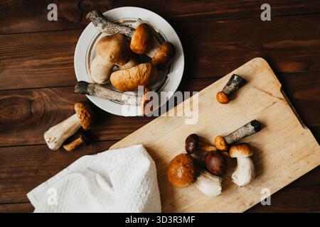 Une scène de cuisine rustique mettant en vedette des champignons boletus et porcini frais sur une planche à découper en bois et dans une assiette, parfait pour la cuisine d'automne et sain Banque D'Images