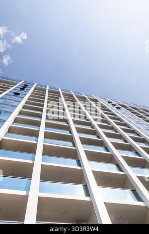 Un immeuble contemporain de grande hauteur dans la ville avec une façade en verre élégante et de multiples espaces de balcon, illustrant la conception architecturale urbaine et Banque D'Images