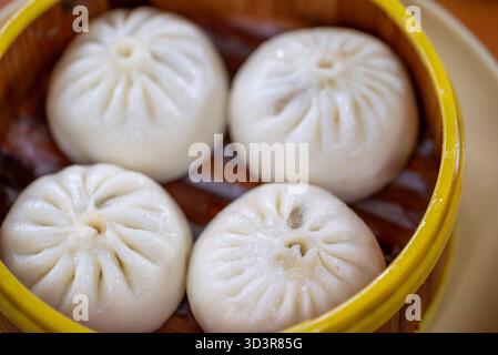 Les baozi moelleux remplis d'ingrédients salés sont soigneusement disposés dans un cuiseur vapeur en bambou. Ce plat traditionnel est apprécié à Chengdu, Sichuan, pendant le déjeuner Banque D'Images