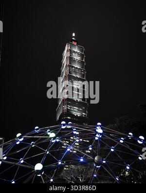 Taipei, Taiwan - 22 mai 2023 : vue de l'imposant Taipei 101 perçant le ciel nocturne, encadrée par une structure de dôme géométrique et lumineuse au premier plan. Banque D'Images