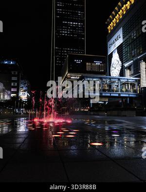 Taipei, Taiwan - 22 mai 2023 : vue d'une fontaine vibrante illuminée en rouge sur le fond sombre d'un paysage urbain moderne, reflétant le noir humide Banque D'Images