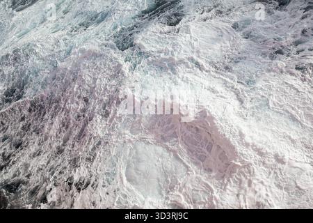 Eau précipitée en pleine mer. Fond d'eau bleu avec mousse blanche Banque D'Images