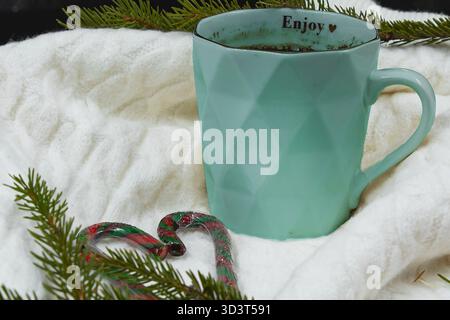 Tasse à la menthe avec boisson chaude sur écharpe blanche et branches de sapin Banque D'Images