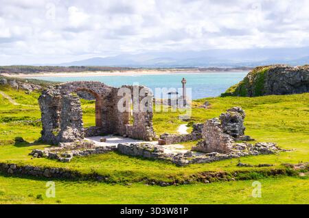 Vue vers les ruines de l'église St Dwynwen et une croix celtique sur l'île de Llanddwyn à Anglesey, pays de Galles Banque D'Images