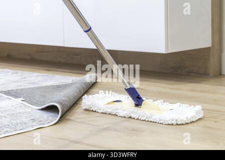 Plancher en bois blanc avec une vadrouille, un concept de service de nettoyage Banque D'Images