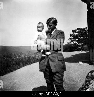 Dr Paul Reiner, un chimiste allemand et professeur, est photographié sur la terrasse de la maison de campagne 'Die Höhe' à Eppenhain, Taunus, vers 1920. La maison appartenait à sa belle-mère, Philippine Hochschild, et la photographie capture Reiner avec une de ses filles, offrant un aperçu de sa vie familiale et du mode de vie bourgeois allemand du début du XXe siècle. Banque D'Images
