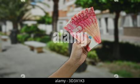 Main tenant cinquante billets de banque philippins peso à l'extérieur dans une rue de la ville, illustrant des thèmes financiers avec un accent sur la monnaie et l'économie dans un vibran Banque D'Images