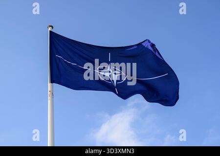 Schoenefeld, Deutschland. 07 novembre 2025. Sur l'image, de gauche à droite : un drapeau sur un mât de drapeau bat dans le vent, logo OTAN OTAN OTAN, bleu et blanc, Conférence de presse 'arrivée du P-8A Poséidon le 7 novembre 2025 - Une nouvelle ère de reconnaissance maritime allemande commence' suivie par - communiqué de presse du ministre fédéral de la Défense Boris Pistorius et commandant de la marine allemande Vice-amiral Axel Deertz à Berlin - Schoenefeld - terminal gouvernemental de l'aéroport de Ber, 7 novembre 2025. Foto Credit : HMB Media/Alamy Live News Banque D'Images