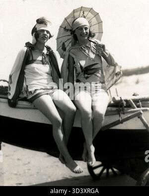 Deux femmes en maillots de bain et foulard assis sur un bateau avec un parasol, daté de 1928. Le paramètre est inconnu. Banque D'Images