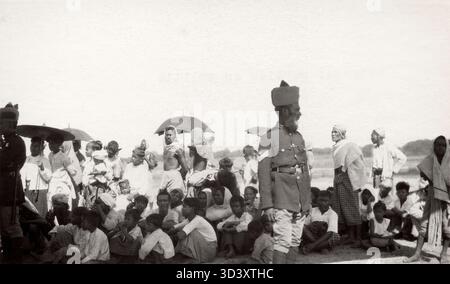 En novembre 1924, le premier vol de KLM vers les Indes orientales néerlandaises se poursuit avec une escale à Rangoon, en Inde, où un policier sikh contrôle la foule de spectateurs attendant le départ du Fokker VII. Banque D'Images