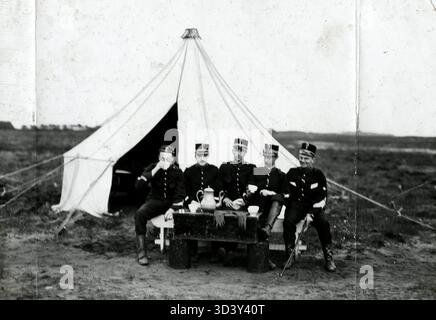 Sous-officiers prenant un thé ou un café à l'extérieur d'une tente dans le camp de tentes de l'Association royale néerlandaise de défense 'Volksweerbaarheid' à Laren, pays-Bas, en 1912. Banque D'Images