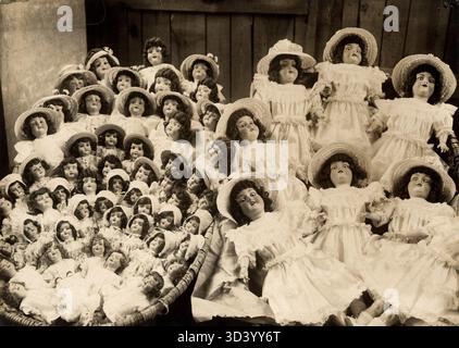 En 1921, des poupées habillées de vêtements élégants avec des chapeaux sont prêtes à la vente chez Loeffler & Dill Doll Factory à Sonneberg, Thüringen, Allemagne. Ceci fait partie d'une série de photos documentant les usines de poupées. Banque D'Images