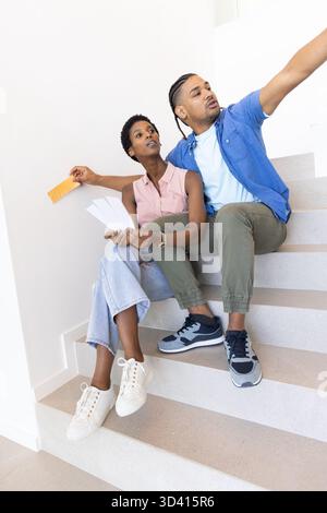 Pointant divers couples choisissant des échantillons de couleur de peinture sur l'escalier de la maison, tenant l'échantillon orange Banque D'Images