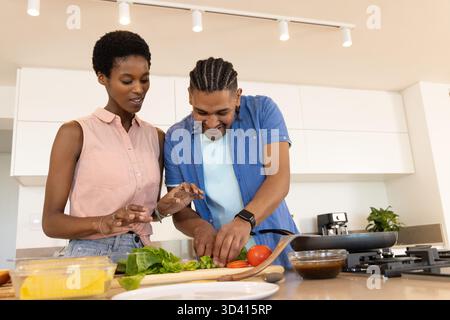 Préparation de divers couples hachant des verts feuillus sur une planche à découper à l'îlot de cuisine, avec bol en verre Banque D'Images