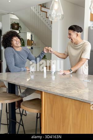 Célébrant divers amis masculins échangeant la première bosse de poing à l'îlot de cuisine en marbre, avec smartwatch Banque D'Images