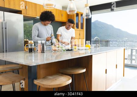 Hacher divers amis masculins préparant le petit déjeuner dans une cuisine moderne, avec avocat et presse française Banque D'Images