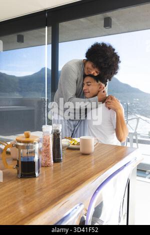 Embrasser divers partenaires masculins partageant le petit déjeuner sur le balcon, avec presse française et vue sur le lac Banque D'Images