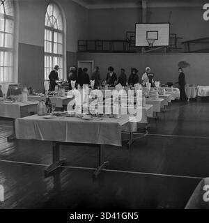 Une photo d'archive de 1984 montre une cantine pour les délégués d'une conférence de la ville à la Maison de la culture Artyom (DK) à Sloviansk, RSS d'Ukraine. Le gymnase, avec son panier de basket-ball et ses fenêtres cintrées, a été temporairement transformé en salle à manger. De longues tables sont dressées avec des repas, y compris des assiettes, des verres et de grandes bouteilles de lait en verre. Cette scène capture la restauration d'un événement soviétique officiel. C'est un moment de la vie quotidienne dans le Donbass paisible avant la guerre. Banque D'Images