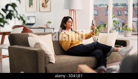 Téléphone, appel vidéo et femme sur le canapé dans l'appartement avec communication, accueil et conversation en ligne. Heureux, ondulant et personne avec téléphone portable pour Banque D'Images