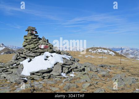 Cairn en pierre avec marqueur de sentier guidant les randonneurs sur un sentier de montagne haut dans les alpes jusqu'au sommet de Schießeck. Styrie, Autriche Banque D'Images