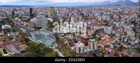 Panorama aérien matinal de Tirana, Albanie, avec une ligne d'horizon moderne, des couleurs d'automne et des chaînes de montagnes lointaines sous un ciel nuageux doux. Banque D'Images