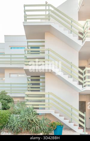 Escalier extérieur d'un immeuble d'appartements blanc moderne avec balustrades vert pastel et jardin au premier plan Banque D'Images