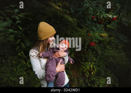 Famille maman avec bébé marchant dans la forêt ensemble vacances voyage style de vie vacances soins de la mère et amour bébé enfant en plein air bonheur Candid emotio Banque D'Images