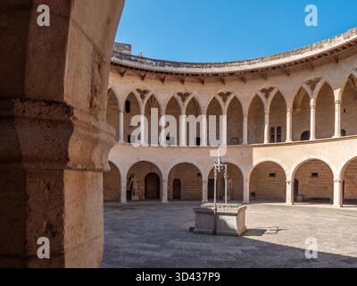Castell de Bellver. Palma de Majorque, une cour circulaire historique dispose d'une fontaine en pierre dans le centre, entourée de colonnades voûtées avec un ciel bleu clair au-dessus de Majorque Banque D'Images