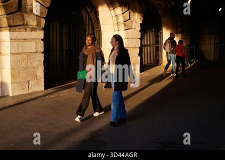 Deux femmes marchant dans une rue de Paris dans la lumière du soir sous une arche, Pont Alexandre III, Paris, France Banque D'Images