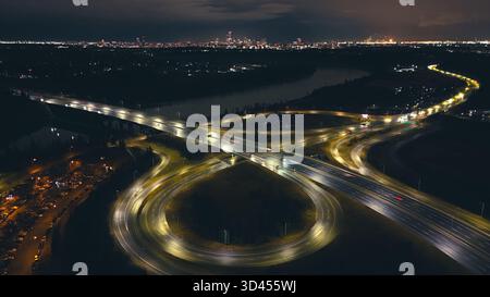 Vue par drone d'une intersection d'autoroute lumineuse formant des schémas de circulation circulaires Banque D'Images
